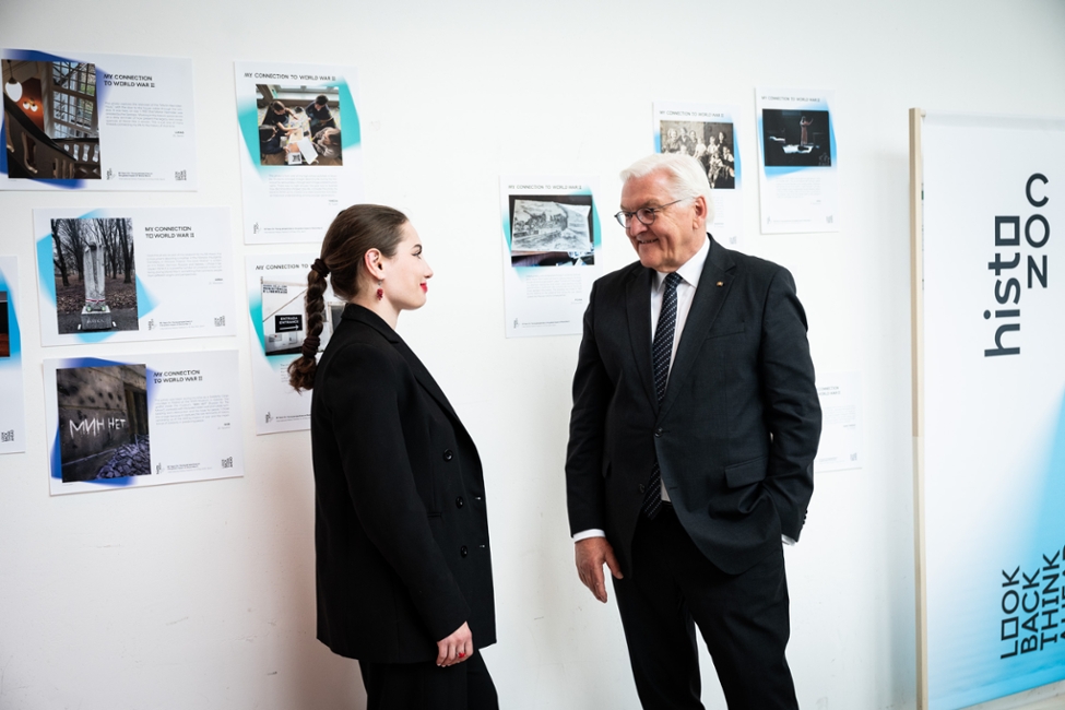 Bundespräsident Steinmeier spricht mit einer jungen Frau. Sie stehen vor einer Wand mit Bildern. (© Bundesregierung/Sandra Steins) Bundespräsident Steinmeier spricht mit einer jungen Frau. Sie stehen vor einer Wand mit Bildern.